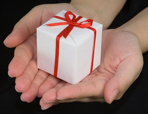 Two outstretched hands offering a small gift-wrapped box