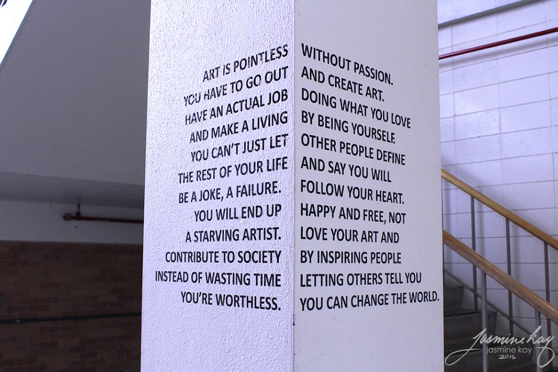 A corner view of two sides of a concrete block with text that reads like disparagement of artistic leanings from one side, but has a completely different message about embracing your true self when both sides are visible. By artist Jasmine Kay.