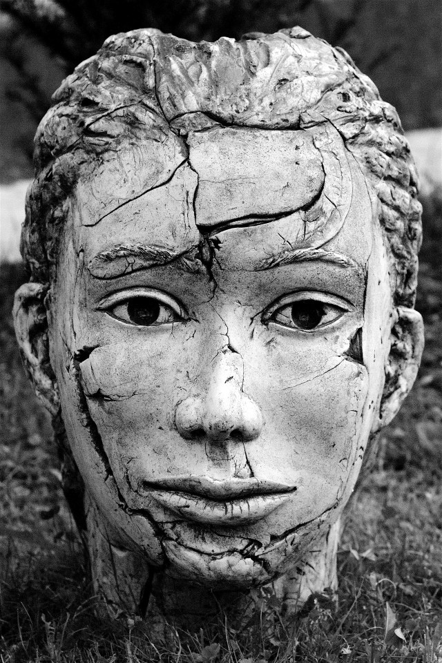 Image by FotoEmotions A statue of a sensitive young face. The statue has been broekn and repaired, so that there are cracks, and small pieces missing from the face.