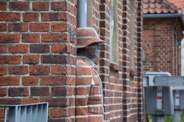 A state of a man made our of bricks is merged with a brick wall