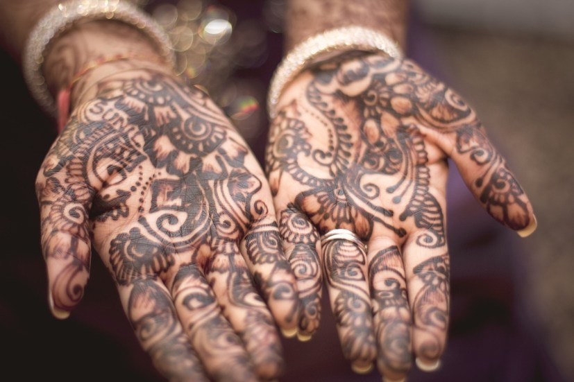 A woman's hands are extended palm up to show intricate henna designs.