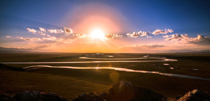 Sunset over a plain with a meandering river looping through it